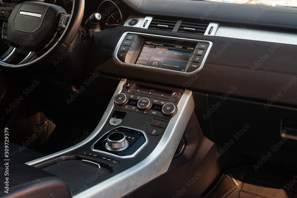 View to the interior of Land Rover Evoque with dashboard, clock, media system, front seats and