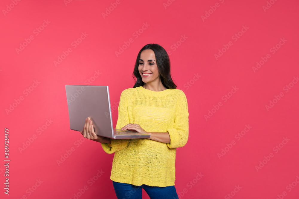 Digital age. Close-up photo of a beautiful manager in casual clothes, who is holding a laptop in her right hand and reading something on the screen while smiling broadly. Digital age. Close-up photo of a beautiful manager in casual clothes, who is holding a laptop in her right hand and reading something on the screen while smiling broadly.