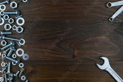 spanners, bolts and nuts on dark wooden surface with copy space