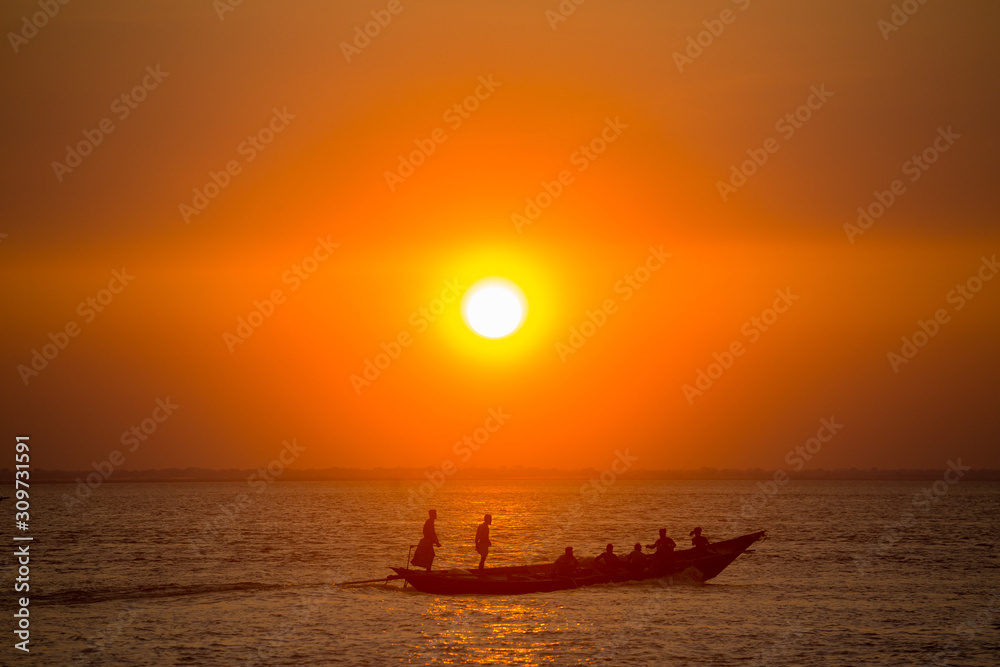 Fototapeta premium Colorful golden Sunset on Sea. Fishermans are returning home with fish, manually at sunset on Char Samarj beach at Chandpur, Bangladesh.