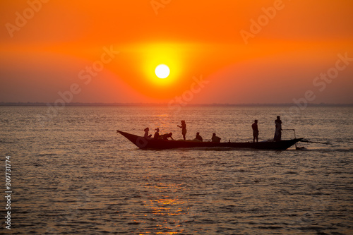 Colorful golden Sunset on Sea. Fishermans are returning home with fish, manually at sunset on Char Samarj beach at Chandpur, Bangladesh.