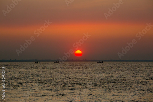 Colorful golden Sunset on Sea. Fishermans are returning home with fish, manually at sunset on Char Samarj beach at Chandpur, Bangladesh. © Onuchcha