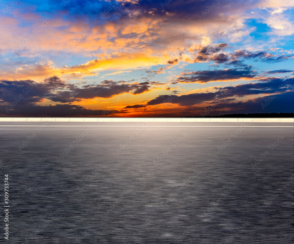 Fototapeta premium Car-free asphalt pavement with sunset sky.