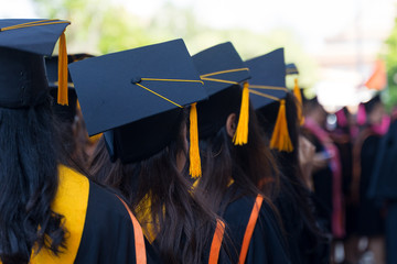Rear view and soft selective focus of the graduates in the graduation commencement ceremony recieving diploma degree certificate.