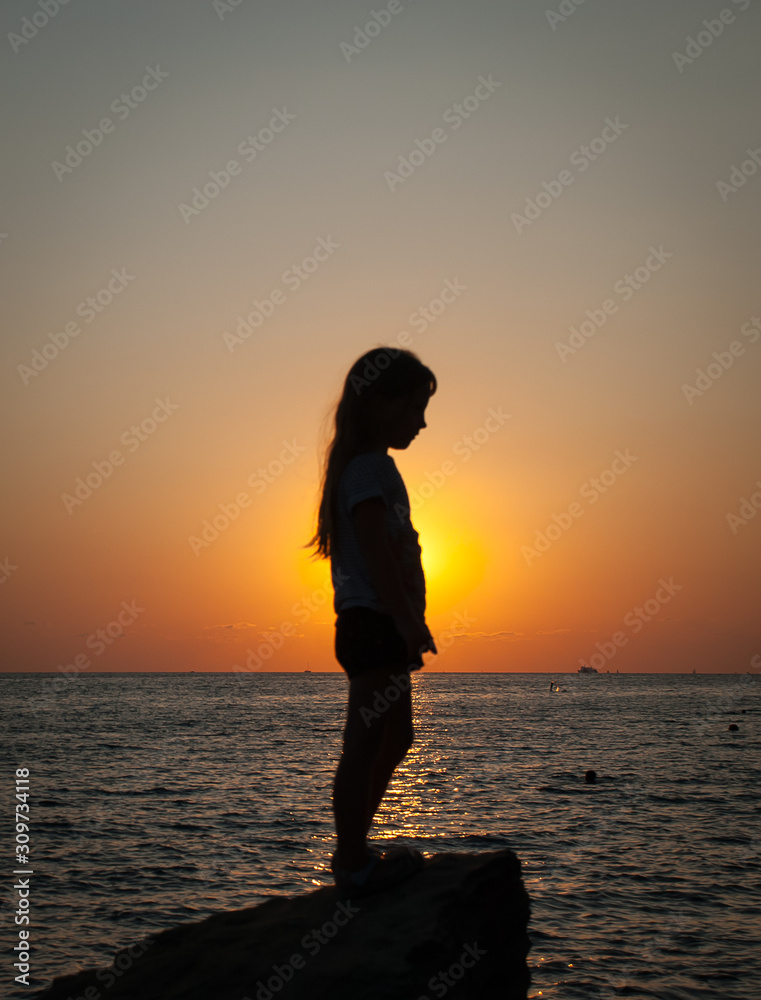 Girl posing on the background of the sea sunset
