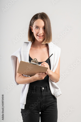 Fotografie Smiling casual woman writing in clipboard