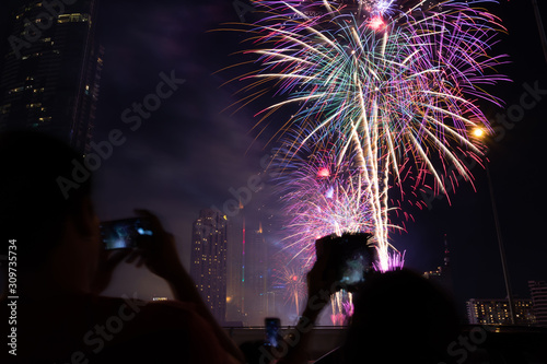Cheering crowd watching fireworks at night; New year concept.