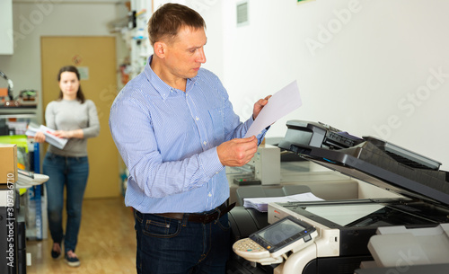 Worker is printing a file, document in the office room