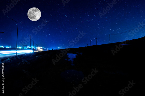 Long exposure shot. Mountain Road through the forest on a full moon night. Scenic night landscape of dark blue sky with moon. Azerbaijan