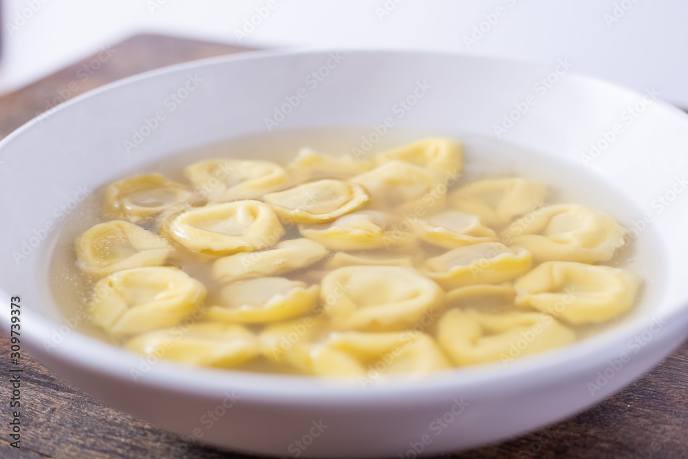 Tortellini in broth. Italian traditional dish. Winter food. Close up view Tortellini in broth. Italian traditional dish. Winter food. Close up view