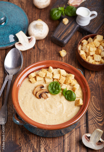 Bowl of champignon mushroom cream soup puree with croutons and basil leaf. Delicious homemade dish. 