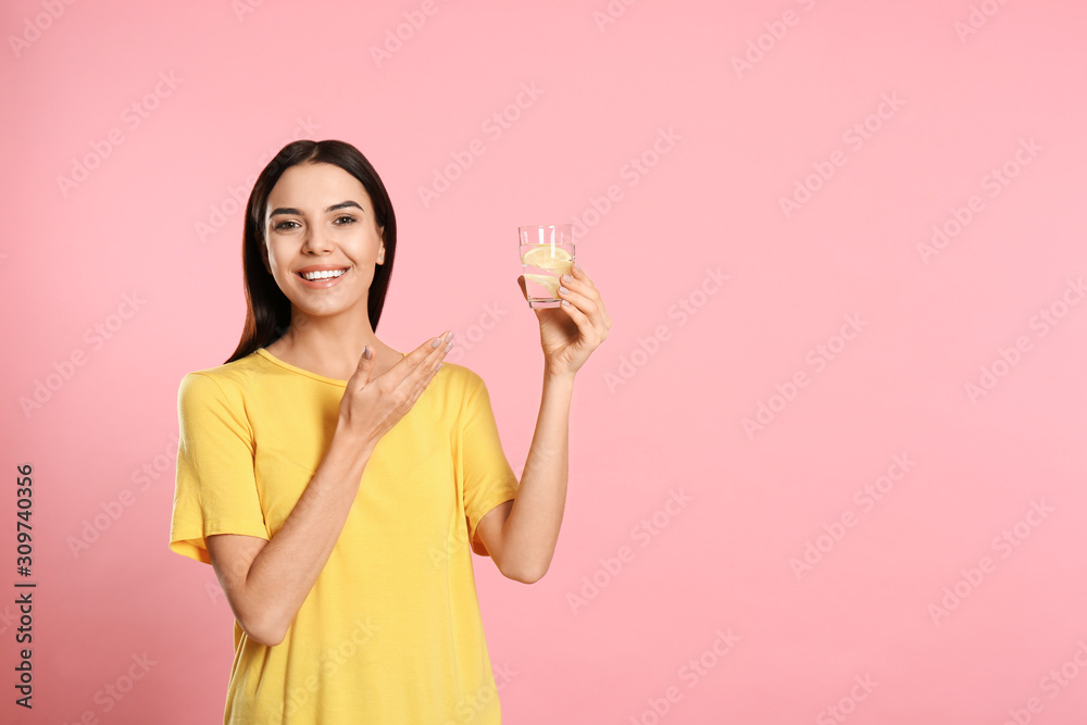 Beautiful young woman with tasty lemon water on pink background. Space for text Beautiful young woman with tasty lemon water on pink background. Space for text