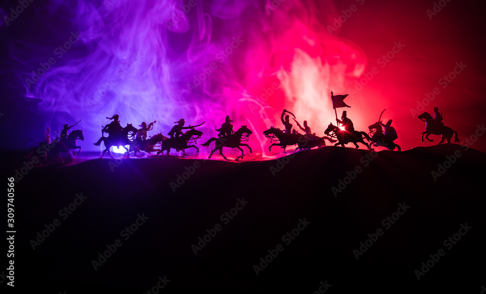 Medieval battle scene with cavalry and infantry. Silhouettes of figures as separate objects, fight between warriors on dark toned foggy background. Night scene.