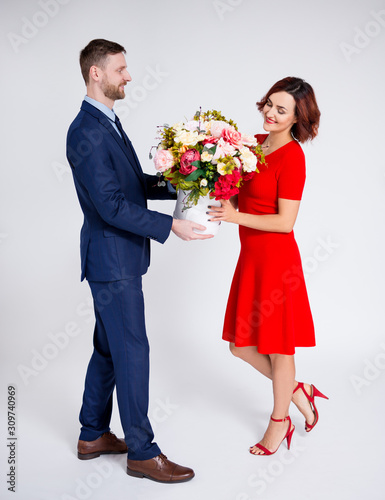 Valentine's day or birthday surprise concept - man surprising his girlfriend with flowers over white