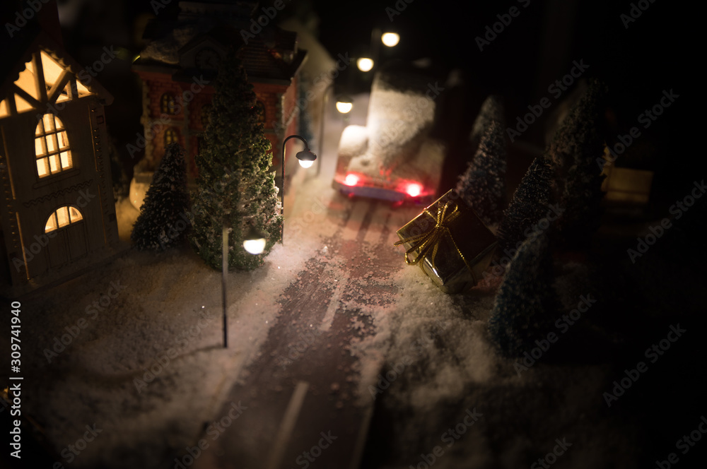 New Year miniature house in the snow at night with fir tree. Holiday concept. Selective focus