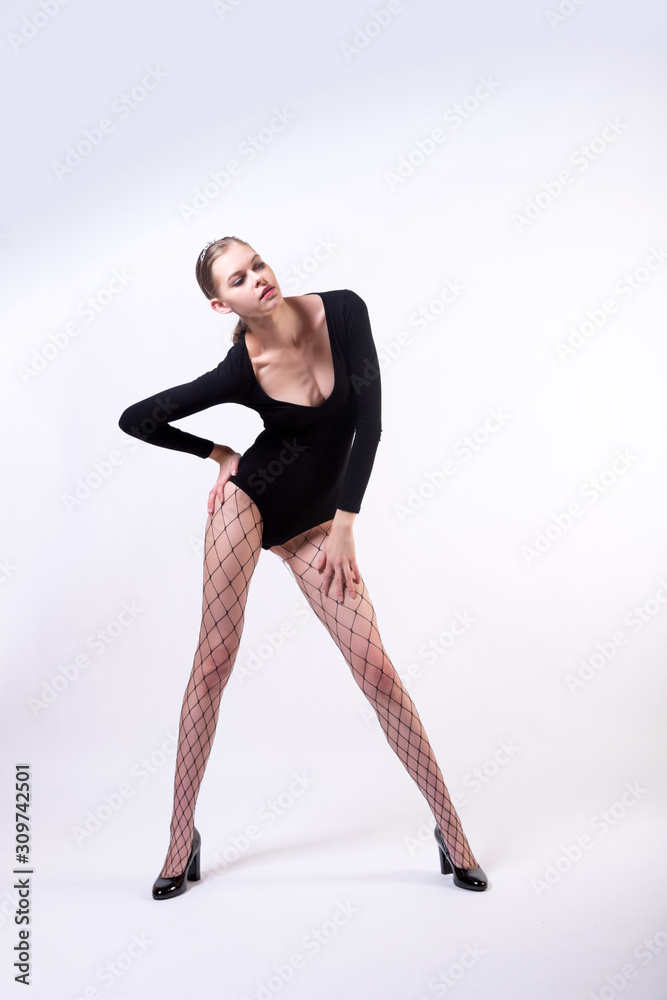 Portrait of a young beauty blondy woman posing in black body, pantyhose and high heels on white isolated background. Stylish girl with an ideal body, model posing training Portrait of a young beauty blondy woman posing in black body, pantyhose and high heels on white isolated background. Stylish girl with an ideal body, model posing training