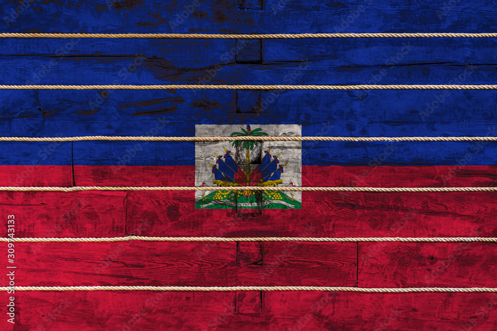 National flag  of  Haiti on a wooden wall background. The concept of national pride and a symbol of the country. Flags painted on a wooden fence with a rope