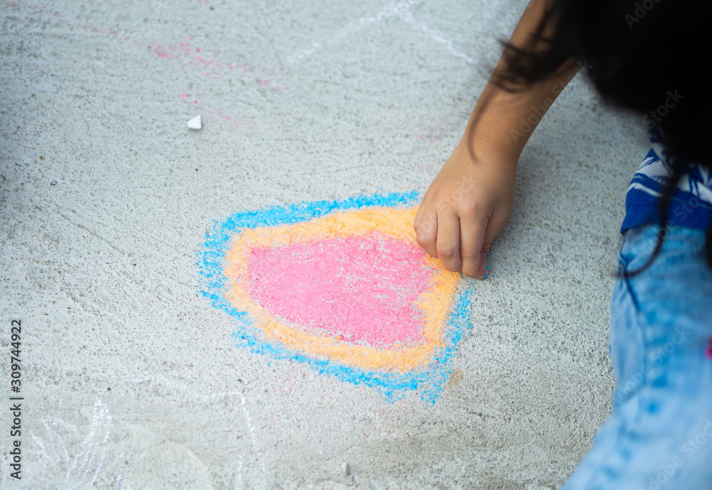 Little asian girl drawing with color chalk on cement floor at school