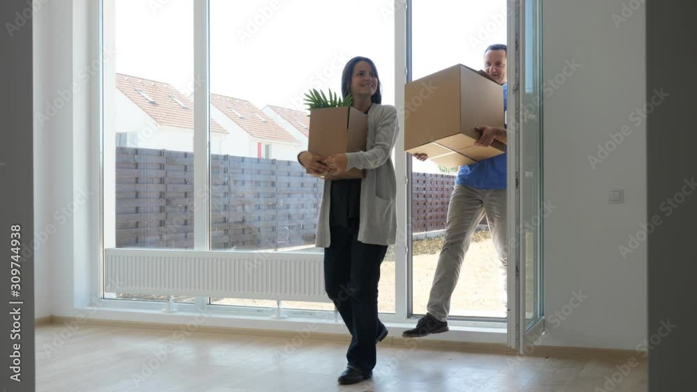 Happy man and woman with cardboard boxes enter in new house, embrace couple Happy man and woman with cardboard boxes enter in new house, embrace couple