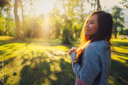 Fotografie Portrait image of a beautiful asian woman standing among nature in the park befo