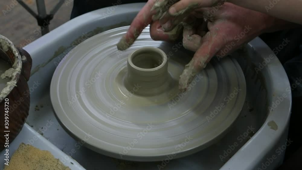 Adult man and child work with clay on a potter's wheel Adult man and child work with clay on a potter's wheel