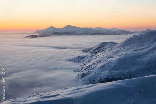 Landscape with high mountains  morning fog and beautiful sunrise. Orange sky. Winter scenery. Wallpaper background. Location place Carpathian  Ukraine  Europe.