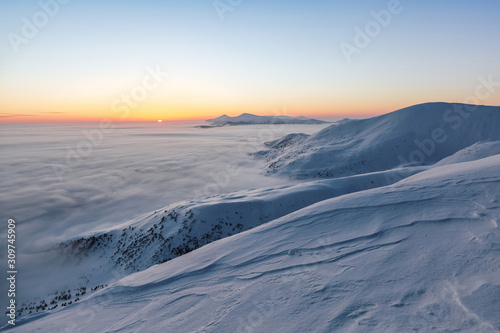 Landscape with high mountains, morning fog and beautiful sunrise. Orange sky. Winter scenery. Wallpaper background. Location place Carpathian, Ukraine, Europe.