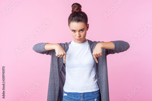 Картината върху платно Here, now! Portrait of demanding girl with bun hairstyle in casual clothes pointing down and looking viciously at camera, naughty teenager requiring to fulfill her whim immediately