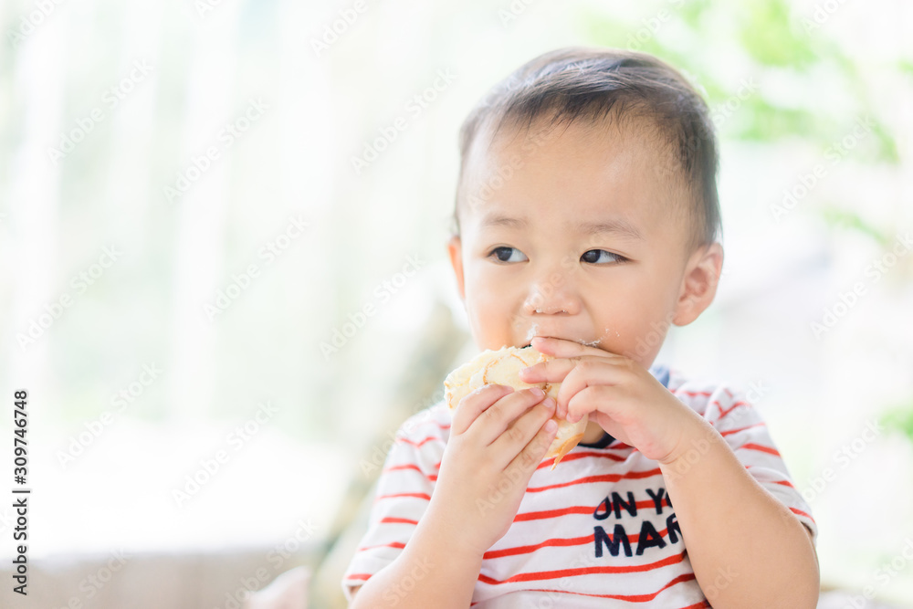 Happy Little asian baby boy eating jam roll at home in summer.Concept for dessert in meal and happy hungry face in food. Happy Little asian baby boy eating jam roll at home in summer.Concept for dessert in meal and happy hungry face in food.