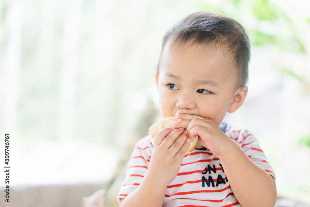 Happy Little asian baby boy eating jam roll at home in summer.Concept for dessert in meal and happy hungry face in food. Happy Little asian baby boy eating jam roll at home in summer.Concept for dessert in meal and happy hungry face in food.