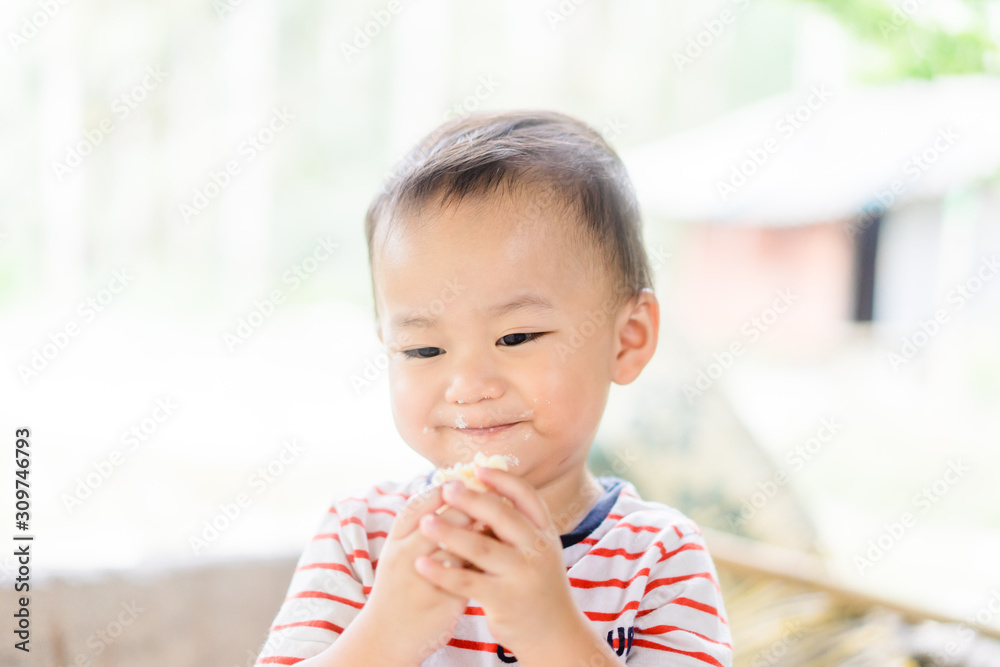 Happy Little asian baby boy eating jam roll at home in summer.Concept for dessert in meal and happy hungry face in food. Happy Little asian baby boy eating jam roll at home in summer.Concept for dessert in meal and happy hungry face in food.
