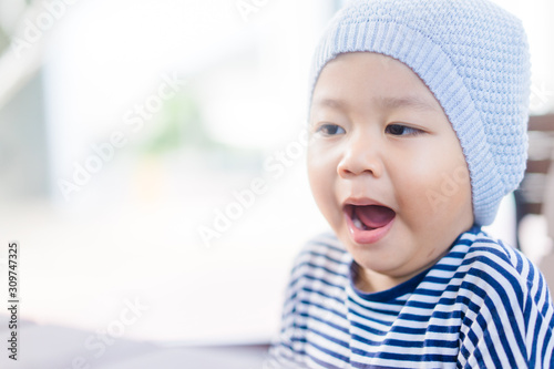 Little asian toddler boy wear hat and yawning in winter time.2 years old boy make sleepy face and tired face.