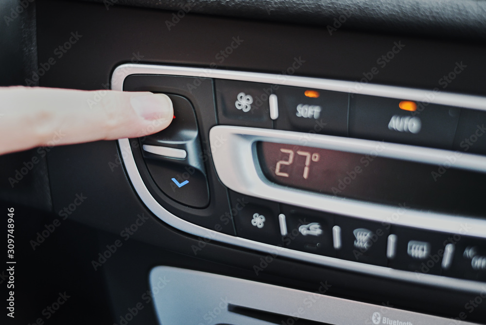 Woman hand set the temperature on air conditioner panel in car. Climate control panel