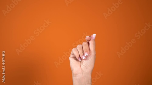 Closeup view of beautiful female hand  isolated on bright orange background. Woman snapping her fingers cheerfully. Real time 4k video footage.