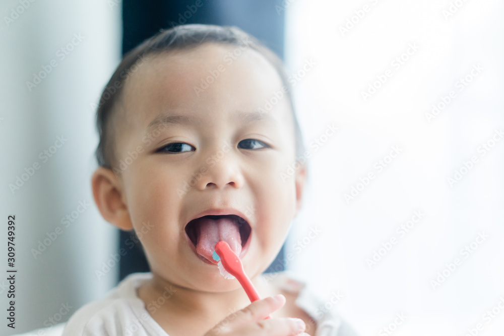kid brushing tongue after brush teeth.2 years old little asian toddler boy brushing teeth.dentistry and oral care concept. kid brushing tongue after brush teeth.2 years old little asian toddler boy brushing teeth.dentistry and oral care concept.