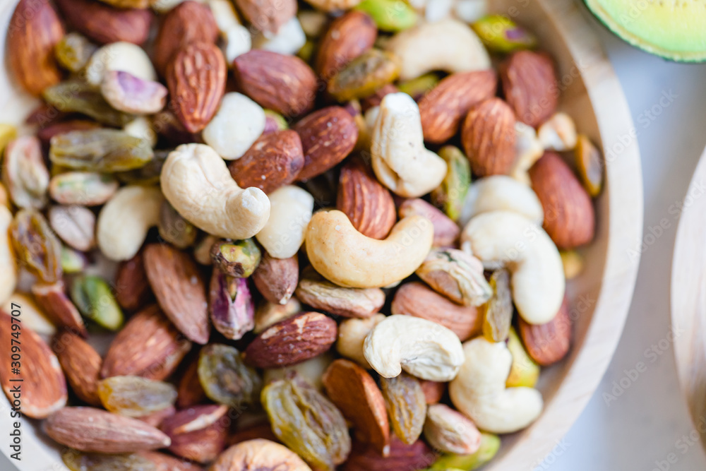 Nuts mix in a wooden plate.Mix nuts with almond, cashew, pistachio, and raisins.Concept of Healthy snack.Vegetarian and Ketogenic diet. Nuts mix in a wooden plate.Mix nuts with almond, cashew, pistachio, and raisins.Concept of Healthy snack.Vegetarian and Ketogenic diet.