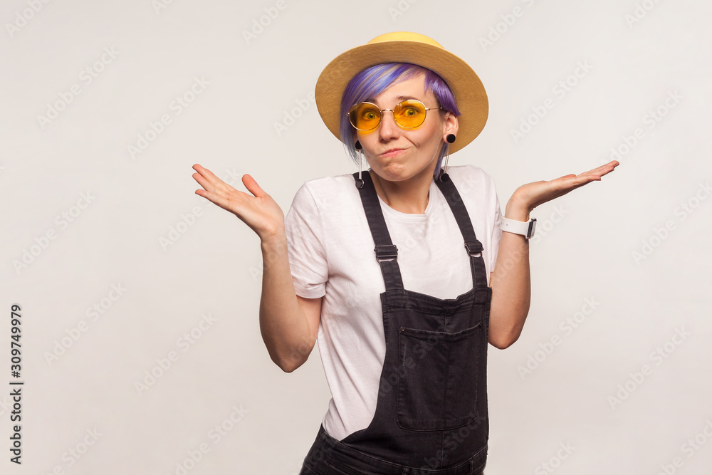No idea. Portrait of confused clueless glamour hipster girl with violet hair in sunglasses and hat shrugging shoulders, doesn't know answer, uncertain puzzled expression. white background, studio shot No idea. Portrait of confused clueless glamour hipster girl with violet hair in sunglasses and hat shrugging shoulders, doesn't know answer, uncertain puzzled expression. white background, studio shot