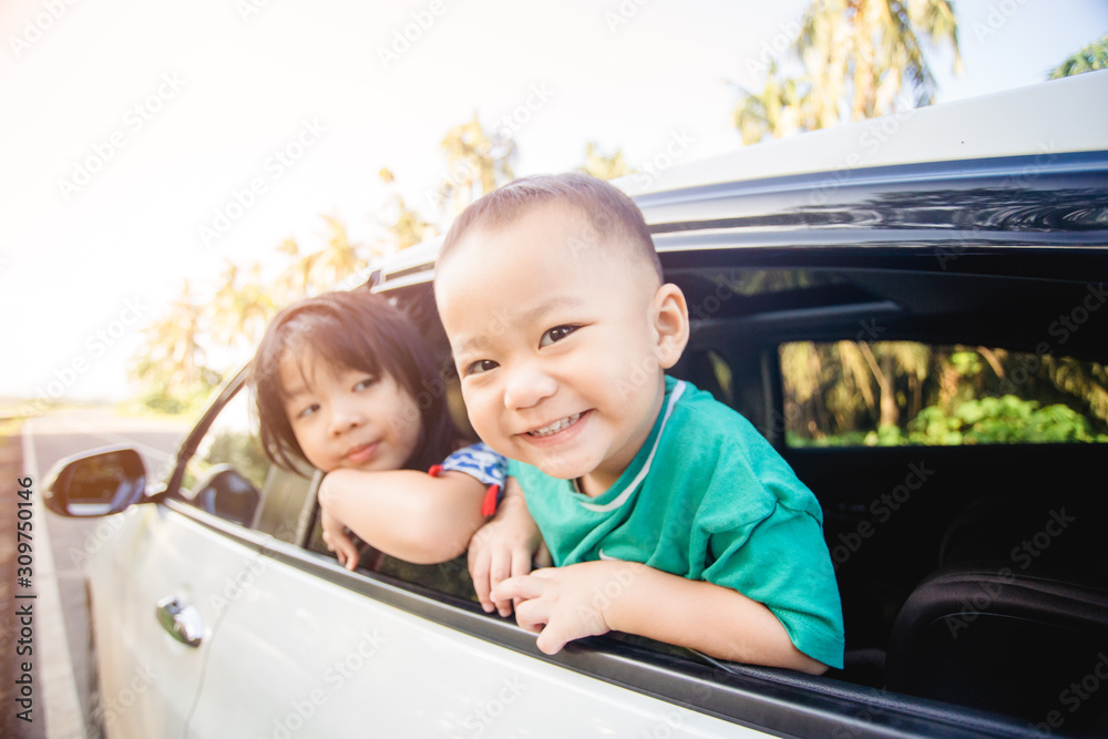 Happy siblings laughing and smiling near window go travel by car against blue sky and coconut trees.Summer road trip, Family with children in car. Happy siblings laughing and smiling near window go travel by car against blue sky and coconut trees.Summer road trip, Family with children in car.