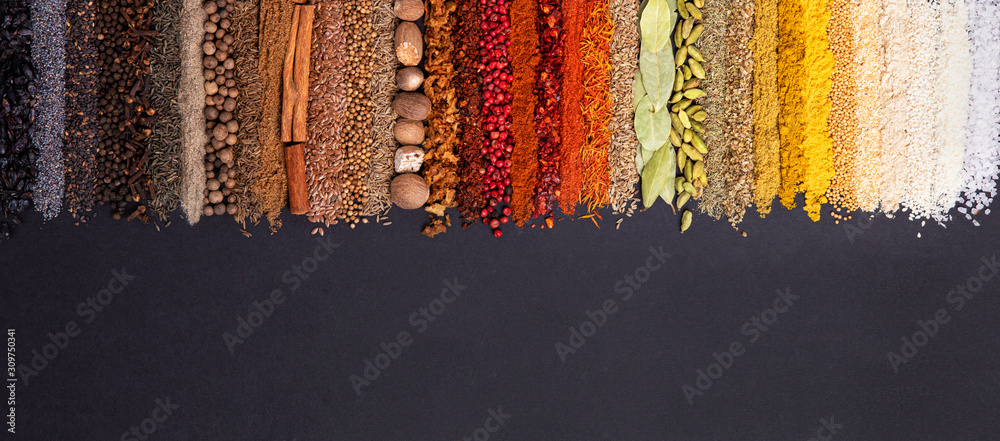 Fototapeta Seasoning, spice and herbs on black background with copy space. Panoramiс background with various condiments for food, top view