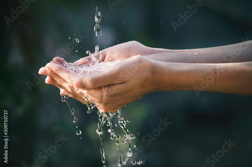 closeup water flow to hand of women for nature concept on the garden background.