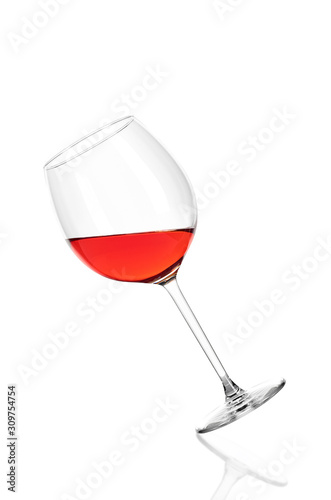 A glass of rose wine half filled, isolated on a white background. The glass is tilted to the left.