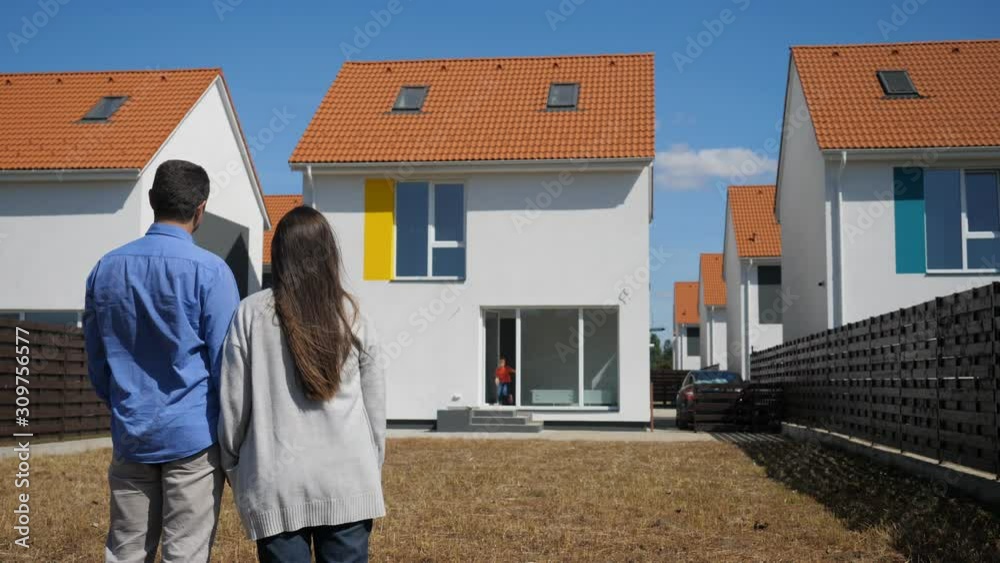 Young couple in the yard in front of their new bought house