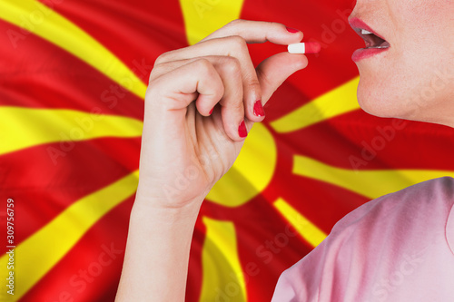 Macedonia health care concept. Close-up of a woman taking vitamin capsule on national flag background.