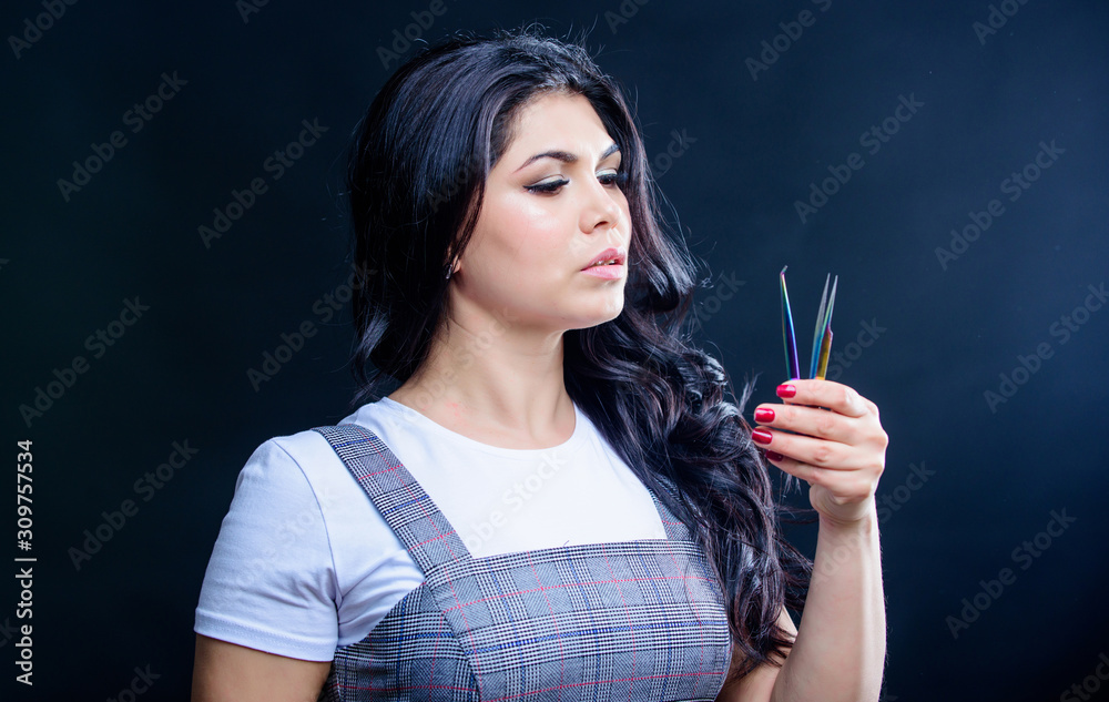 Obraz premium Getting ready to the night out. cosmetologist with special tool for eyebrows. pretty woman eyelash master hold tweezers. Eyebrow Correction. beautician in beauty salon. Eyelash extension procedure