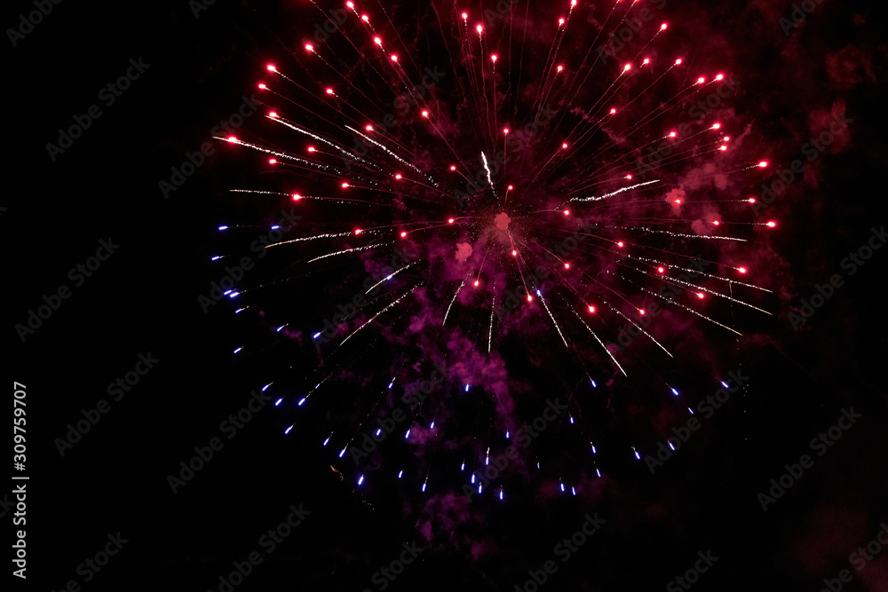 Fototapeta premium Night sky salute. A photo of a salute in the sky. Abstract salute texture. Texture of bright lights, abstract figures in the sky. Multicolored flares of lights. Photo for textures and processing