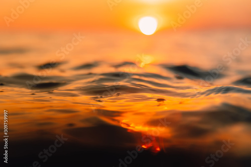 Sunset and waves in ocean. Warmy water texture with bokeh photo