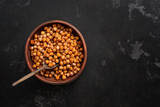 A bowl of fried chickpeas on a dark stone background. Top view, flat lay, copy space.