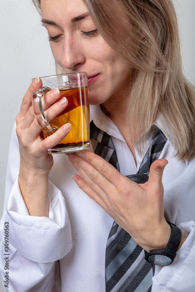 A blond woman in a white shirt and tie is drinking tea. There is a break in the train. A blond woman in a white shirt and tie is drinking tea. There is a break in the train.