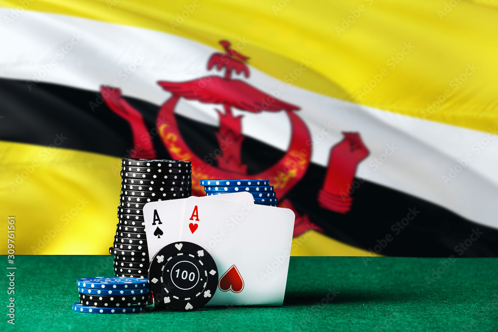 Brunei casino theme. Two ace in poker game, cards and black chips on green table with national flag background. Gambling and betting.