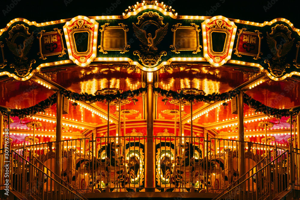 partial view of beautiful carousel with many light at night in theme park